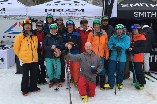 Group of skiers smiling with Smith and Prizm Lens Technology tents behind them
