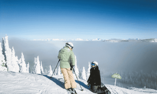 Skier and snowboarder talking at the top of a mountain slope