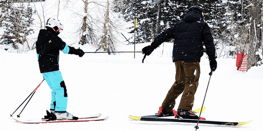 Ski instructor teaching a child how to ski with a pull rope