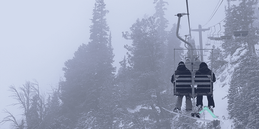 People sitting on a chairlift on a foggy day